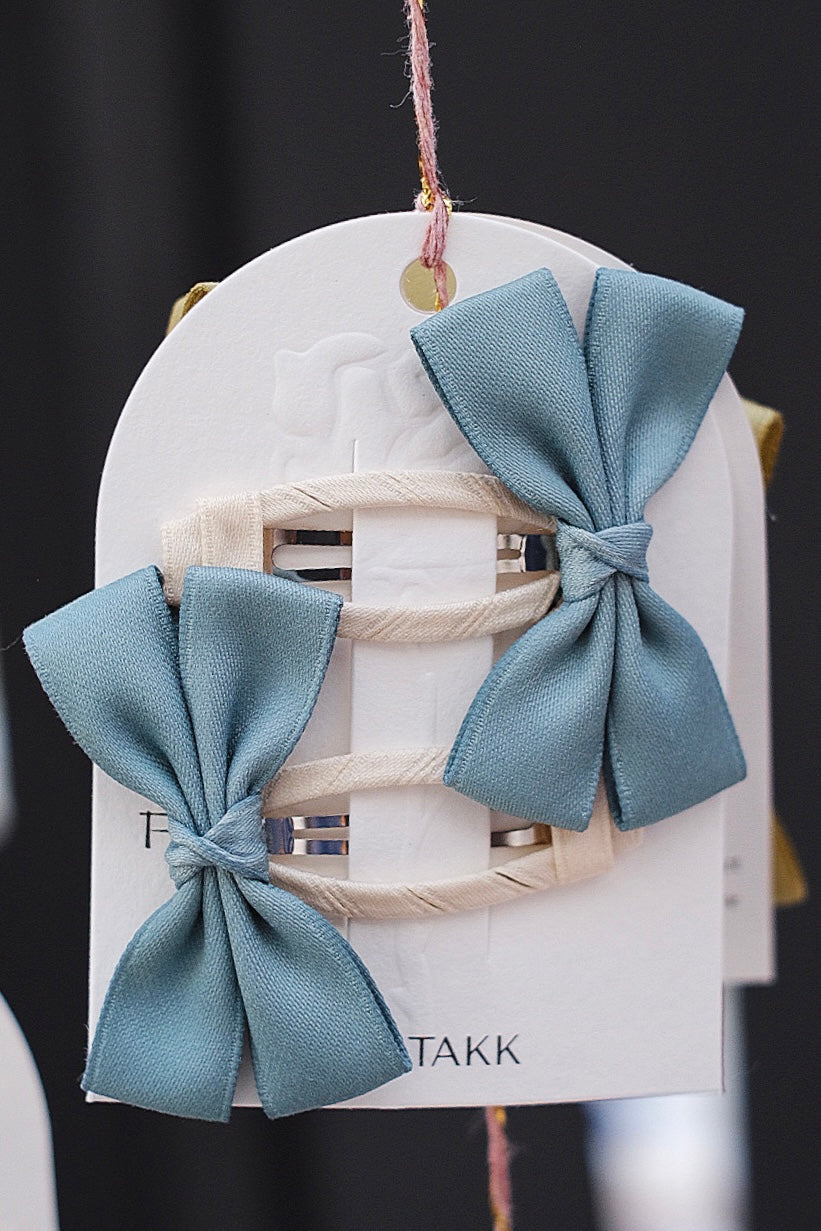 A set of light blue bow hair clips, adding a serene and calming touch.
