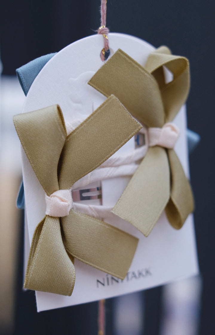 A set of muted green bow hair clips, offering a subtle and elegant style.