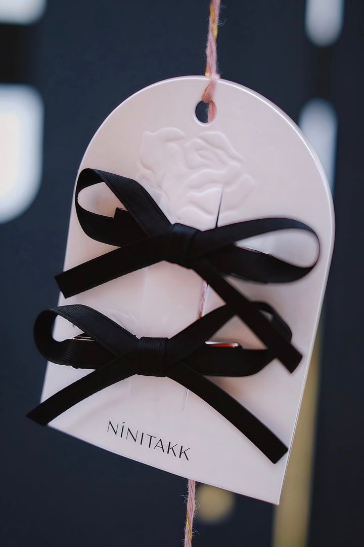 A pair of deep black bow hair clips set. The bows feature a classic design, perfect for adding a touch of elegance to any hairstyle.