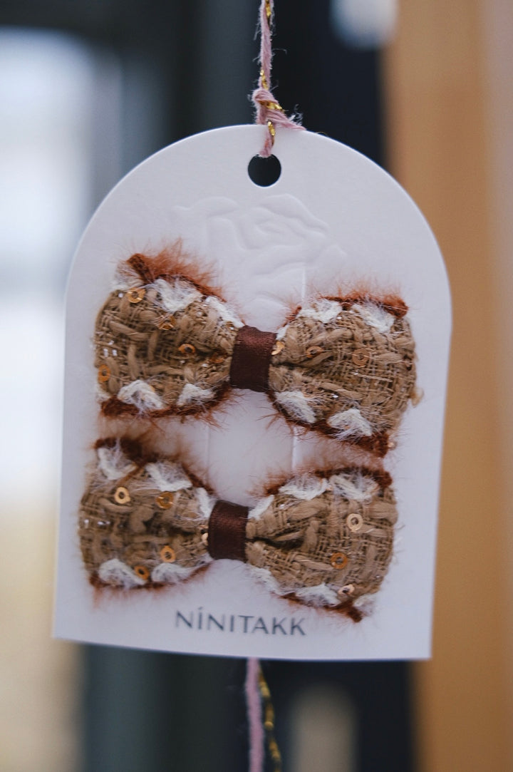 A soft beige fluffy bow, providing a cozy and neutral touch to any winter ensemble.