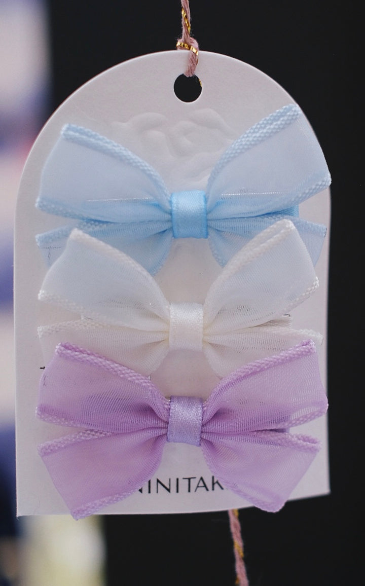 A serene collection of pastel-colored hair clips in blue, lavender, and white, showcasing their delicate bow designs.