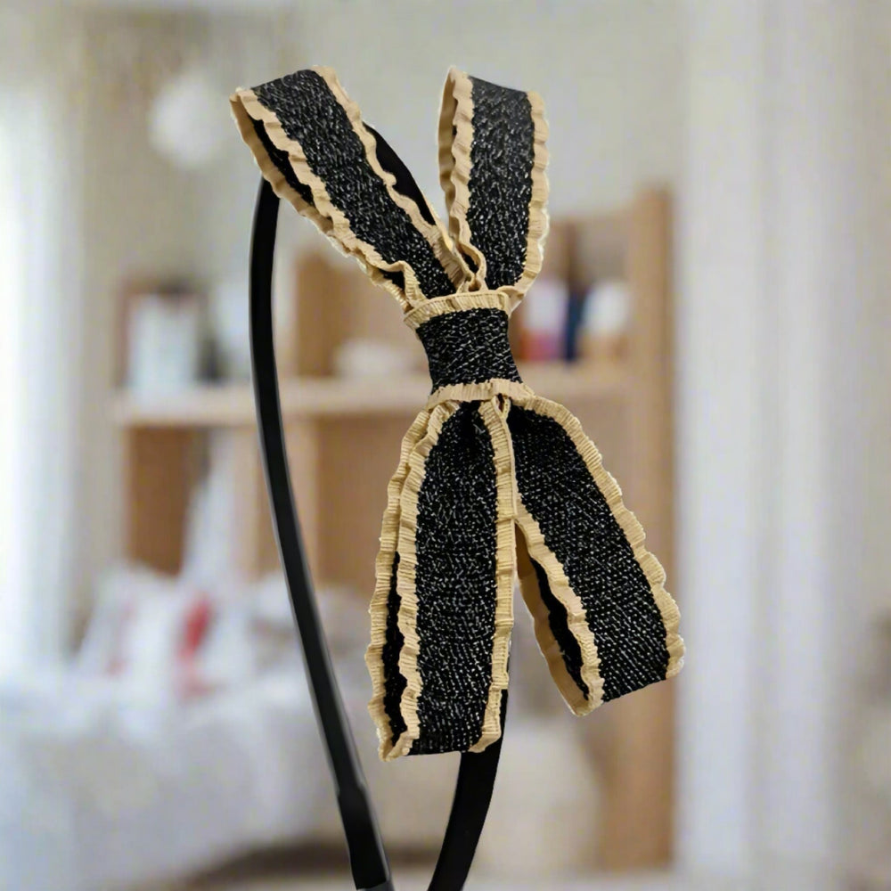 This charming headband showcases a beautifully crafted black and beige ruffled bow, providing a unique and textured look. The 9 cm double-layer fabric bow is designed to make a stylish statement while ensuring comfort.