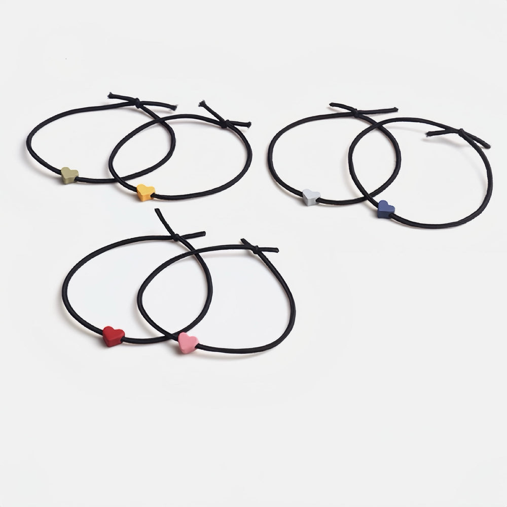 Set of six elastic hair ties, each with a tiny heart in different colors—deep blue, yellow, bright red, pink, light purple, and green—arranged on a white background.