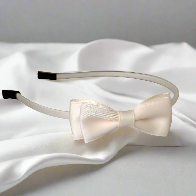 This delicate headband showcases a creamy ivory satin bow, offering a classic and versatile look. The mid-size double-layer bow, measuring around 7.5 cm, is perfect for both formal occasions and everyday wear.