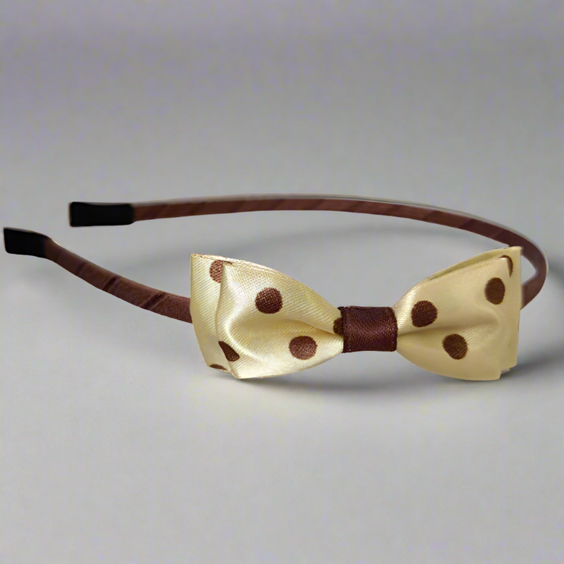 This headband features a luxurious golden satin bow adorned with playful brown polka dots. The mid-size double-layer bow, approximately 7.5 cm in length, sits atop a sturdy iron headband, perfect for adding a touch of elegance to any outfit.