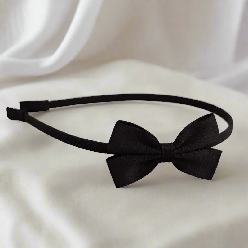 A sophisticated black headband with a small, stylish bow, perfect for a sleek and polished look. The bow is made from a soft cotton-blend material, adding comfort and style.