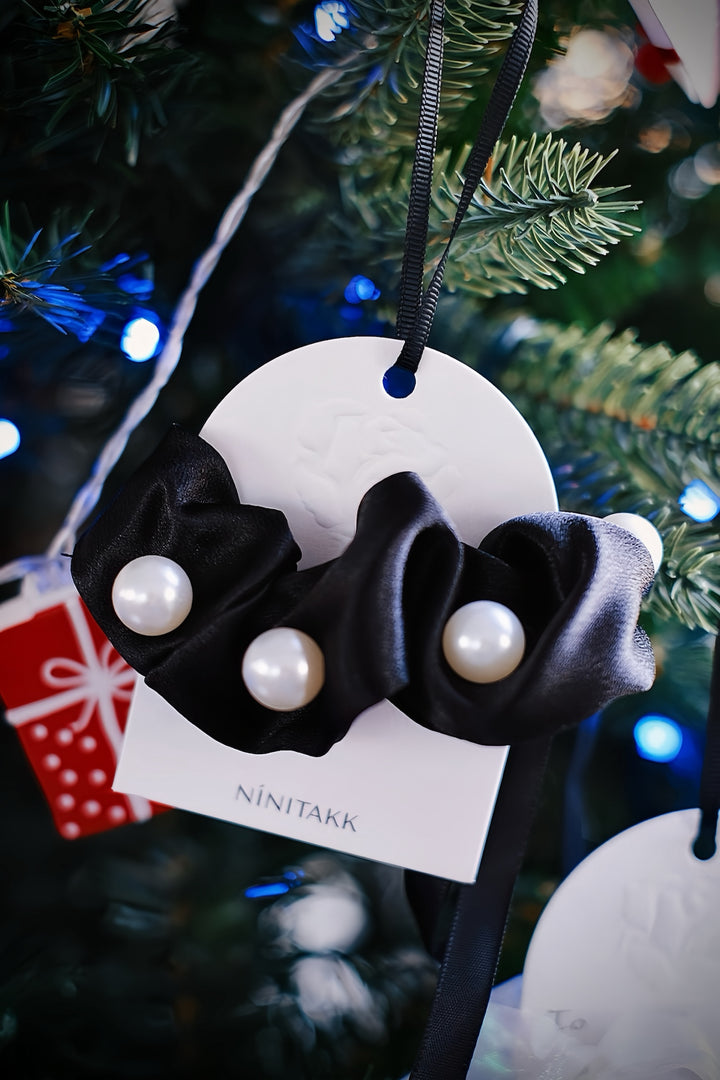 This scrunchie is made of soft black satin and big imitation pearls, complete with a long bow that flows in the back.