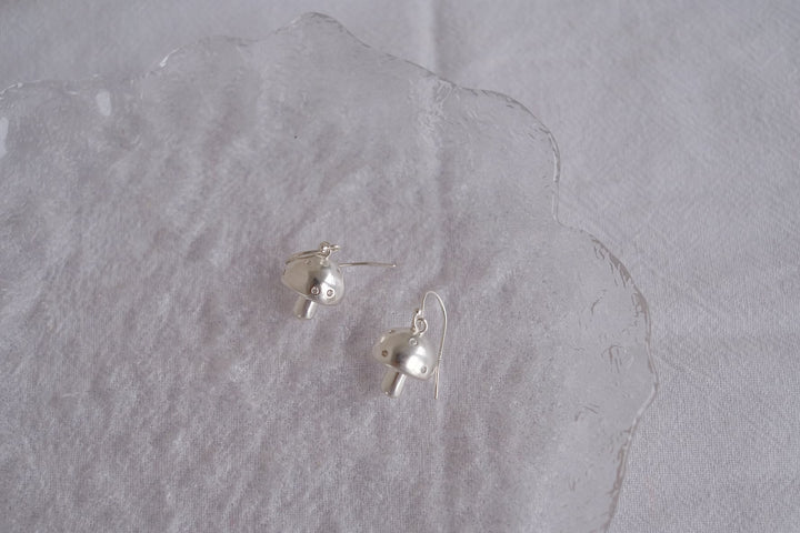 Pair of sterling silver mushroom earrings displayed on a white background, emphasizing their cute and whimsical design.