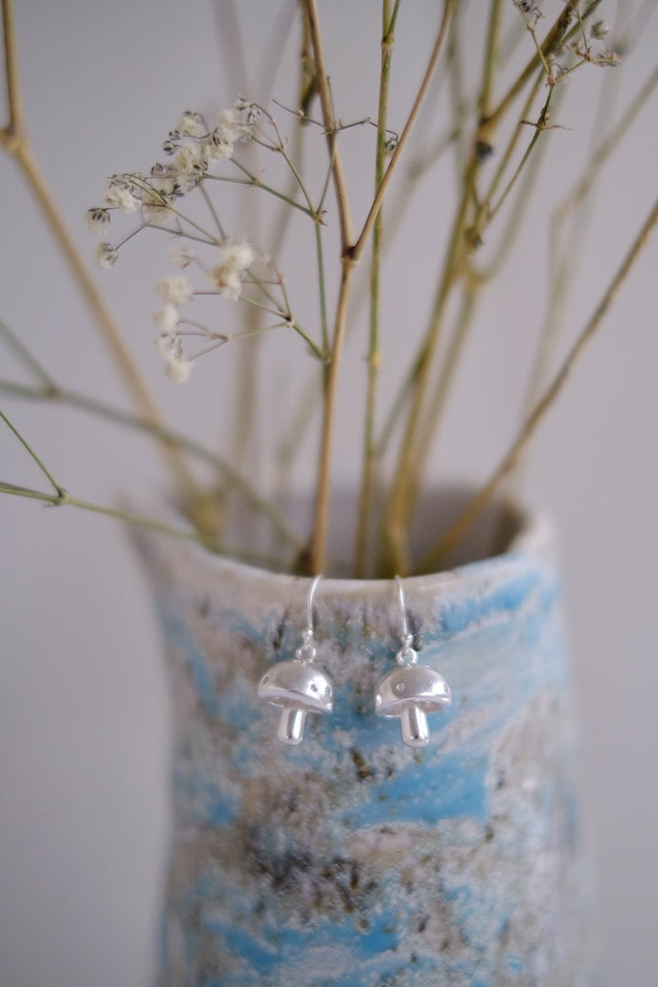 Sterling silver mushroom earrings dangling from a vase, suitable for women and girls.