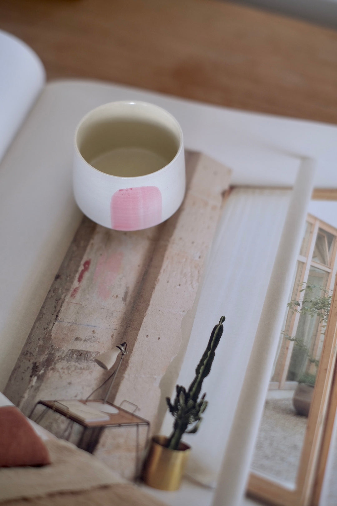 A top-down angle reveals the cup’s refined interior, with a smooth, natural finish. The soft pink accent on the exterior contrasts beautifully with the minimalist white ceramic, making it a visually appealing addition to any tea or coffee setup.