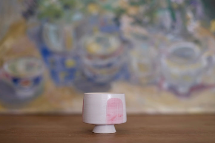 A side view of the ceramic cup showcases its modern, clean lines and blush pink accent. The smooth, rounded form and small footed base give it a balanced and elegant look, perfect for an espresso or a delicate tea ritual.