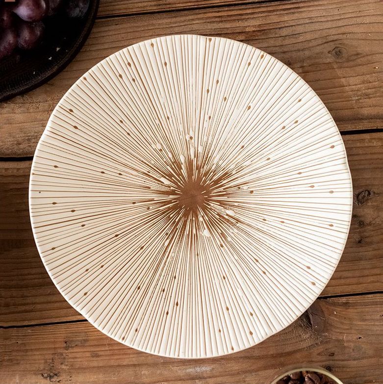 Top-down view of the white ceramic plate with delicate gold radial lines, showcasing its intricate design and smooth finish.