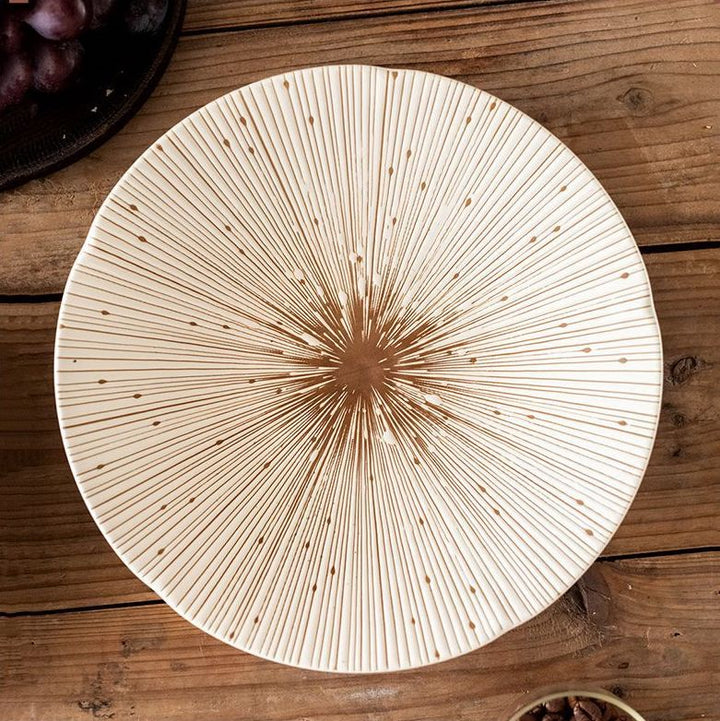 Top-down view of the white ceramic plate with delicate gold radial lines, showcasing its intricate design and smooth finish.