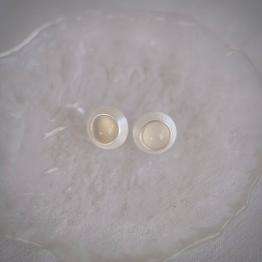 These Goddess Stud Earrings showcase the delicate white agate gemstone. The translucent stone is encircled by a gleaming sterling silver halo, offering a soft and luminous appearance perfect for day or night.