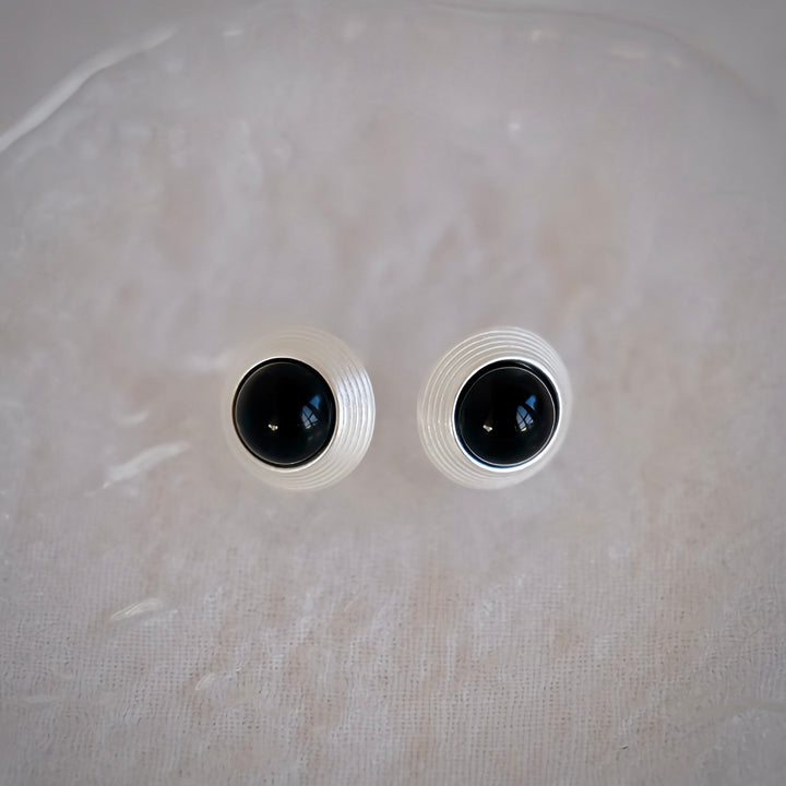 The Goddess Stud Earrings with deep black onyx create a striking contrast against their sterling silver setting. The bold, dark stone is elegantly highlighted by the silver frame, adding a touch of mystery and sophistication to any look.