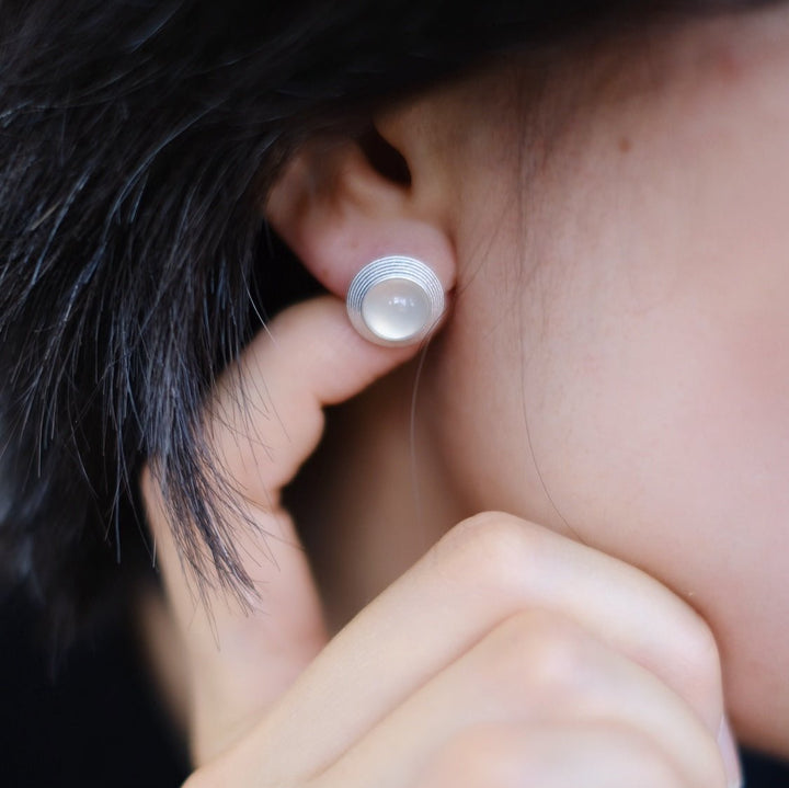 Worn on a model, the Goddess Stud Earrings reveal their size and the intricate detail of their craftsmanship. The soft, matte finish of the silver and the smooth, polished gemstones are evident in this close-up.