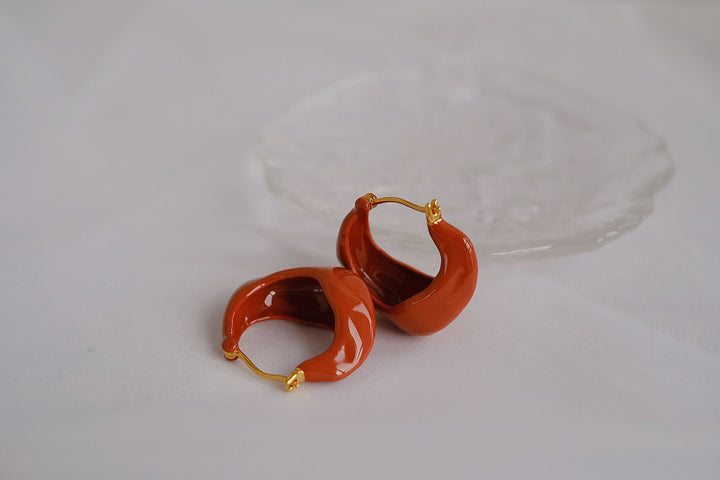 The red wavy hoop earrings are paired with a gold toned post.