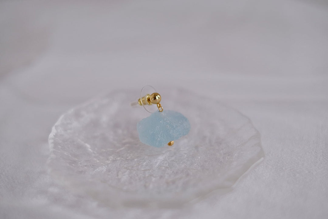 The blue crystal earring, focusing on its tranquil aquamarine shade and the shimmering gold accents.
