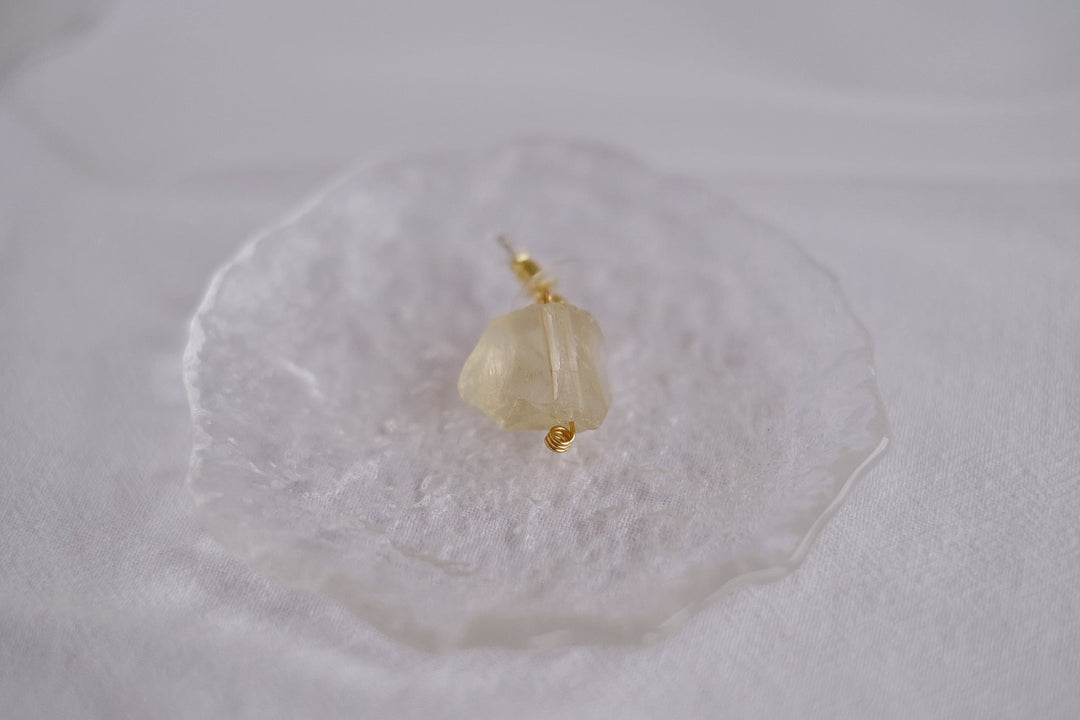 The yellow crystal earring, highlighting the warm citrine tones and the intricate gold-plated design.