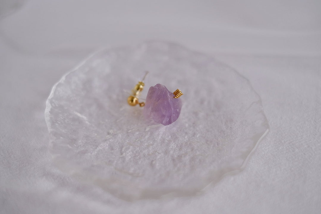 A detailed view of the purple crystal earring with its rich amethyst hue, highlighting the 18k gold plated post and brass body.
