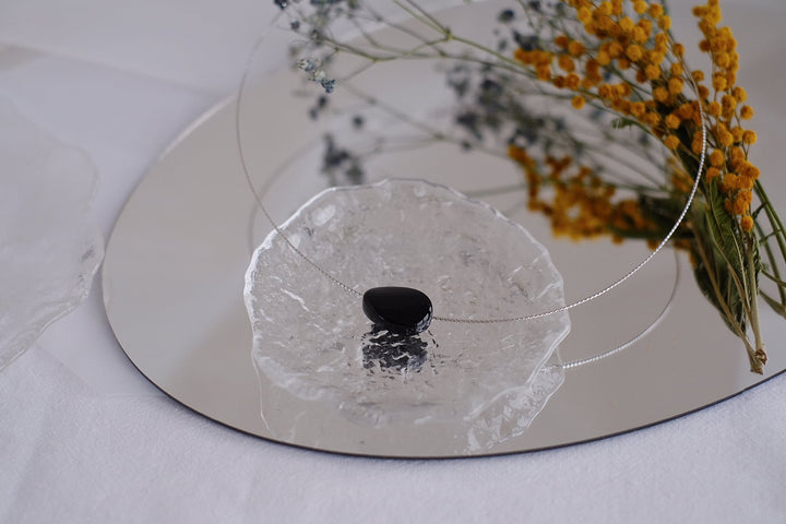 The Liquorice choker displayed on a glass dish.