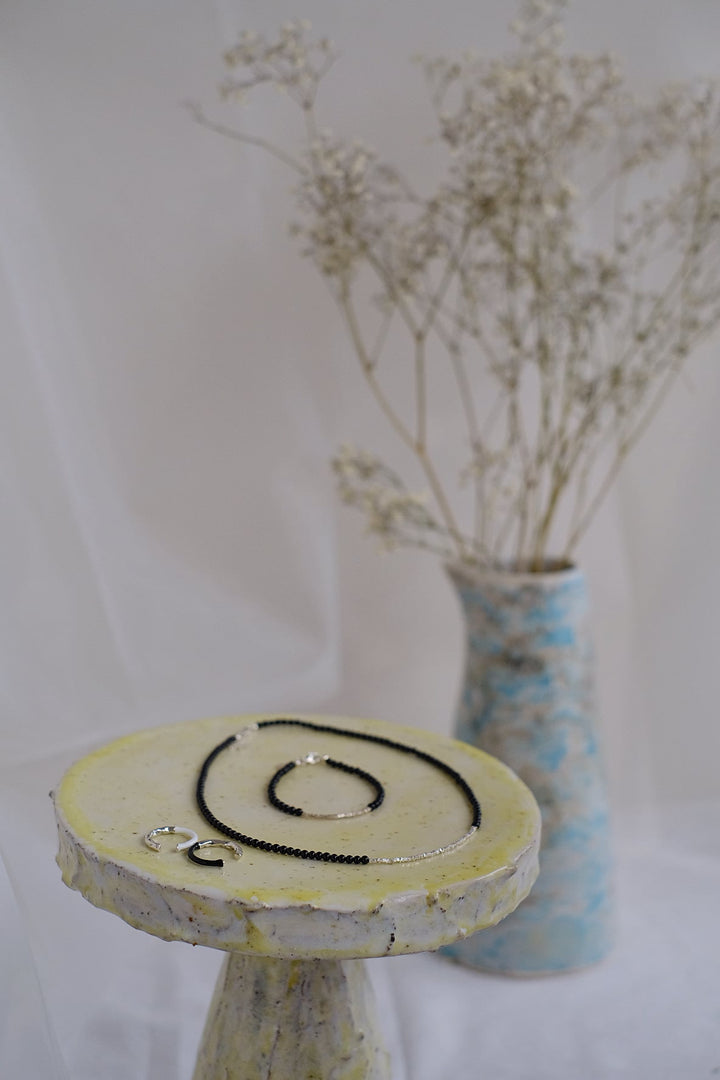 The Ice Beach bracelet and necklace displayed together on a stylish jewelry stand, with a floral background emphasizing their elegance.