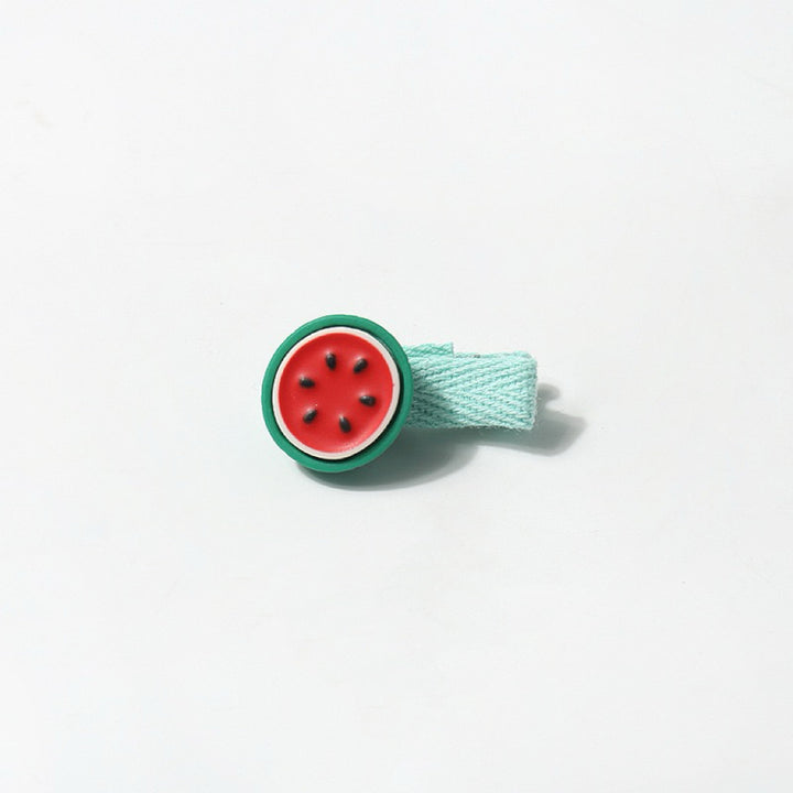 A close-up image of the watermelon hair clip, featuring a vibrant red and green design with black seed details and a soft, pastel blue fabric wrapping.