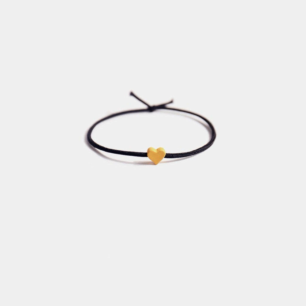 Close-up of a single hair tie with a tiny yellow heart, showcasing its cute and colorful design.
