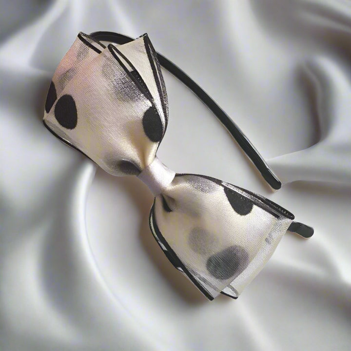 This headband features an eye-catching off-white silk yarn bow adorned with large black polka dots, adding a touch of playful elegance to any girl's ensemble. The triple-layer bow is approximately 12 cm, making it a standout accessory for both casual and festive occasions.