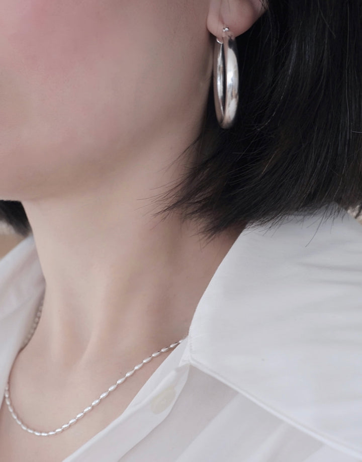 The chunky hoop earrings worn with a casual outfit, illustrating their versatility and elegance.