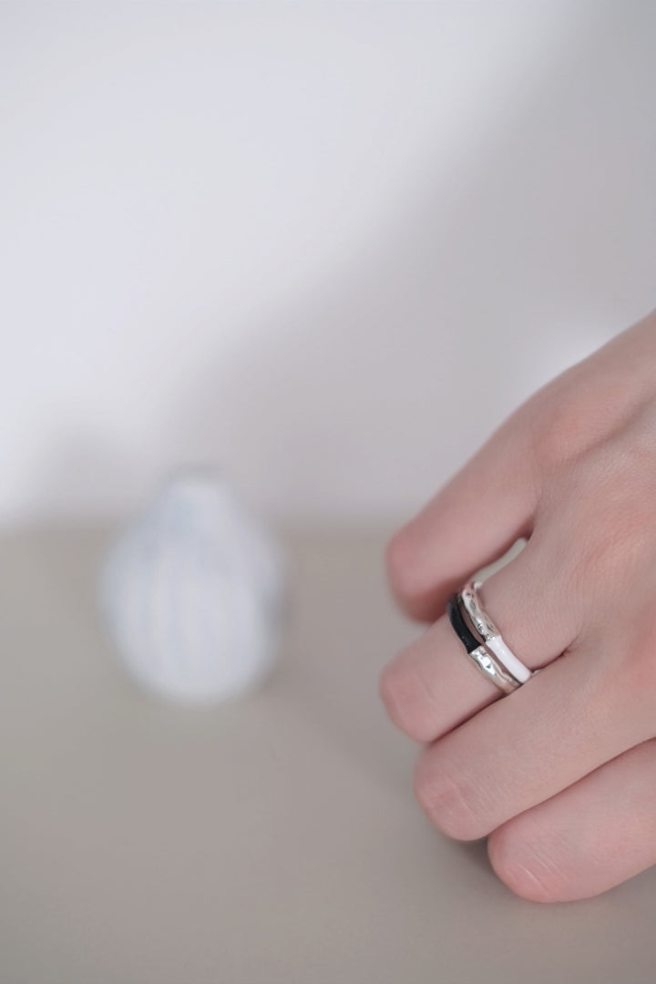 Pair of rings displayed side by side, highlighting the contrasting colors of the white and black enamel glaze against the sterling silver base.