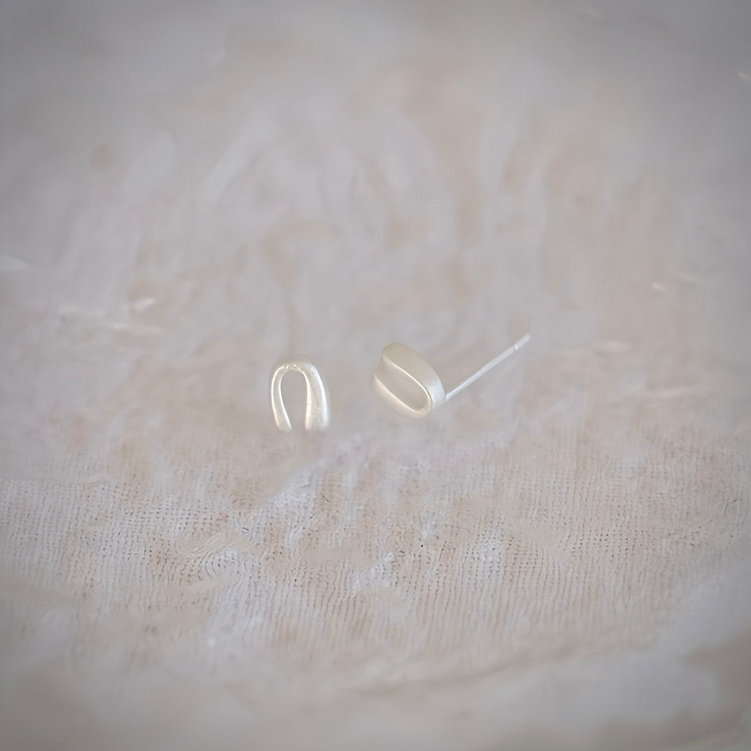 A pair of Mini Horseshoe earrings in sterling silver, showcasing its delicate design and perfect horseshoe curve against a clean background.