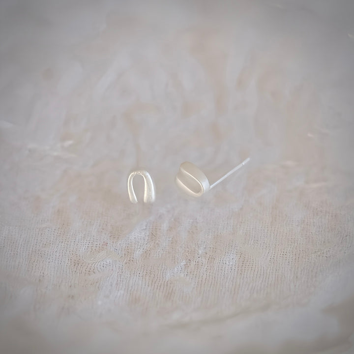 A pair of Mini Horseshoe earrings in sterling silver, showcasing its delicate design and perfect horseshoe curve against a clean background.