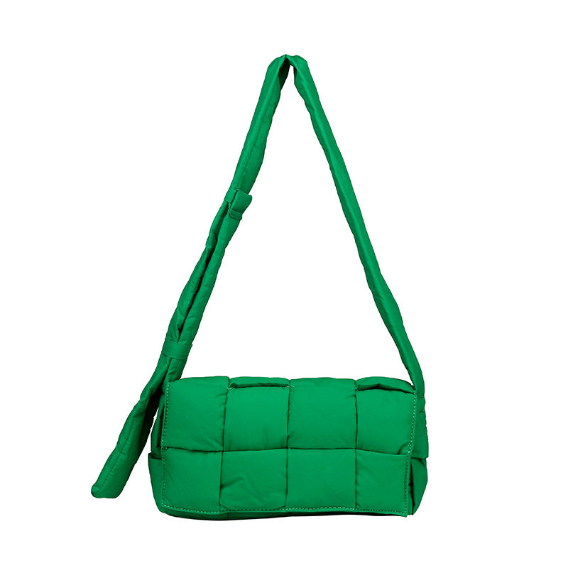 The image showcases the quilted shoulder bag in lush green, highlighting its unique quilted pattern and adjustable shoulder strap.