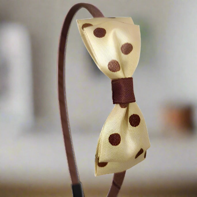 Displaying a side perspective, this image captures the bow's layered satin texture and the comfortable fit of the iron headband. The golden bow with brown polka dots adds a chic touch to any look, perfect for both festive and everyday wear.