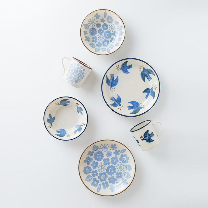 An overhead group view displaying the Minoyaki seabird plates alongside matching mugs from the series. This image highlights the beautiful, subdued blue design and the retro coloring of each piece, emphasizing their elegance and versatility.