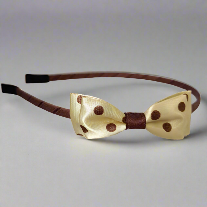 This headband features a luxurious golden satin bow adorned with playful brown polka dots. The mid-size double-layer bow, approximately 7.5 cm in length, sits atop a sturdy iron headband, perfect for adding a touch of elegance to any outfit.