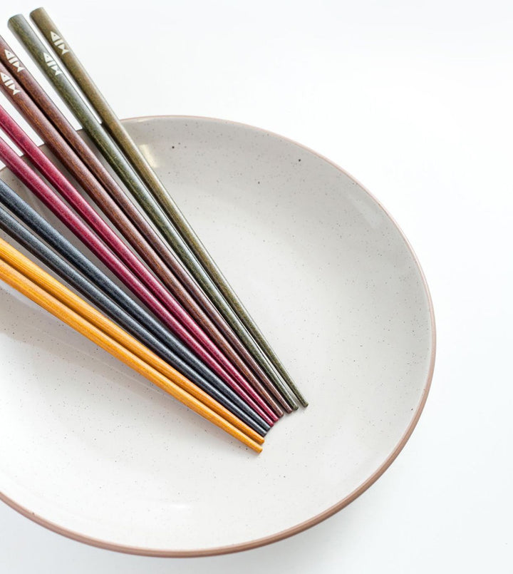 Side view of the chopsticks, highlighting their pointed tips and natural wood texture.