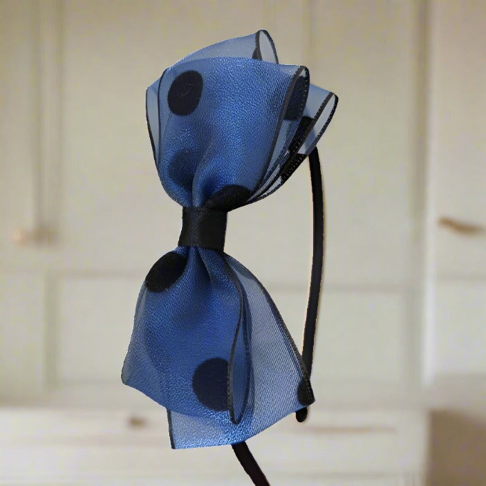 Featuring a striking large silk yarn bow with oversized polka dots on a rich deep blue fabric, this headband combines elegance with a whimsical touch, perfect for girls who love a bit of flair in their style.
