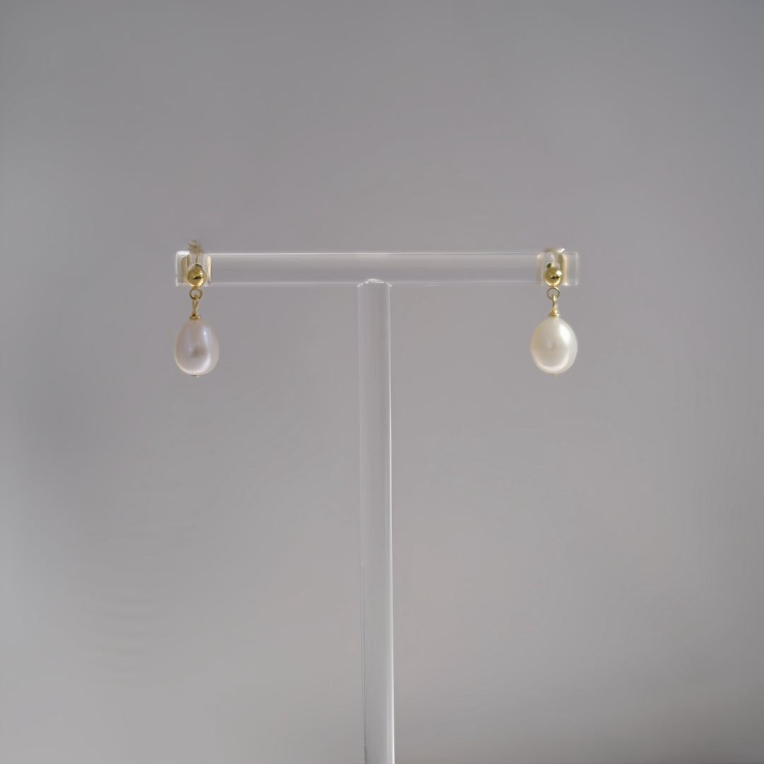 A detailed view of the Petite Pearl Drop Earrings, highlighting the small freshwater pearls and the 14k gold-filled sterling silver posts.