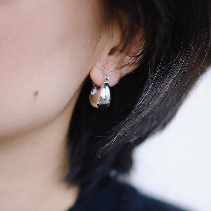 A model wearing the sterling silver Vessel Earrings, demonstrating their comfortable fit and elegant appearance.