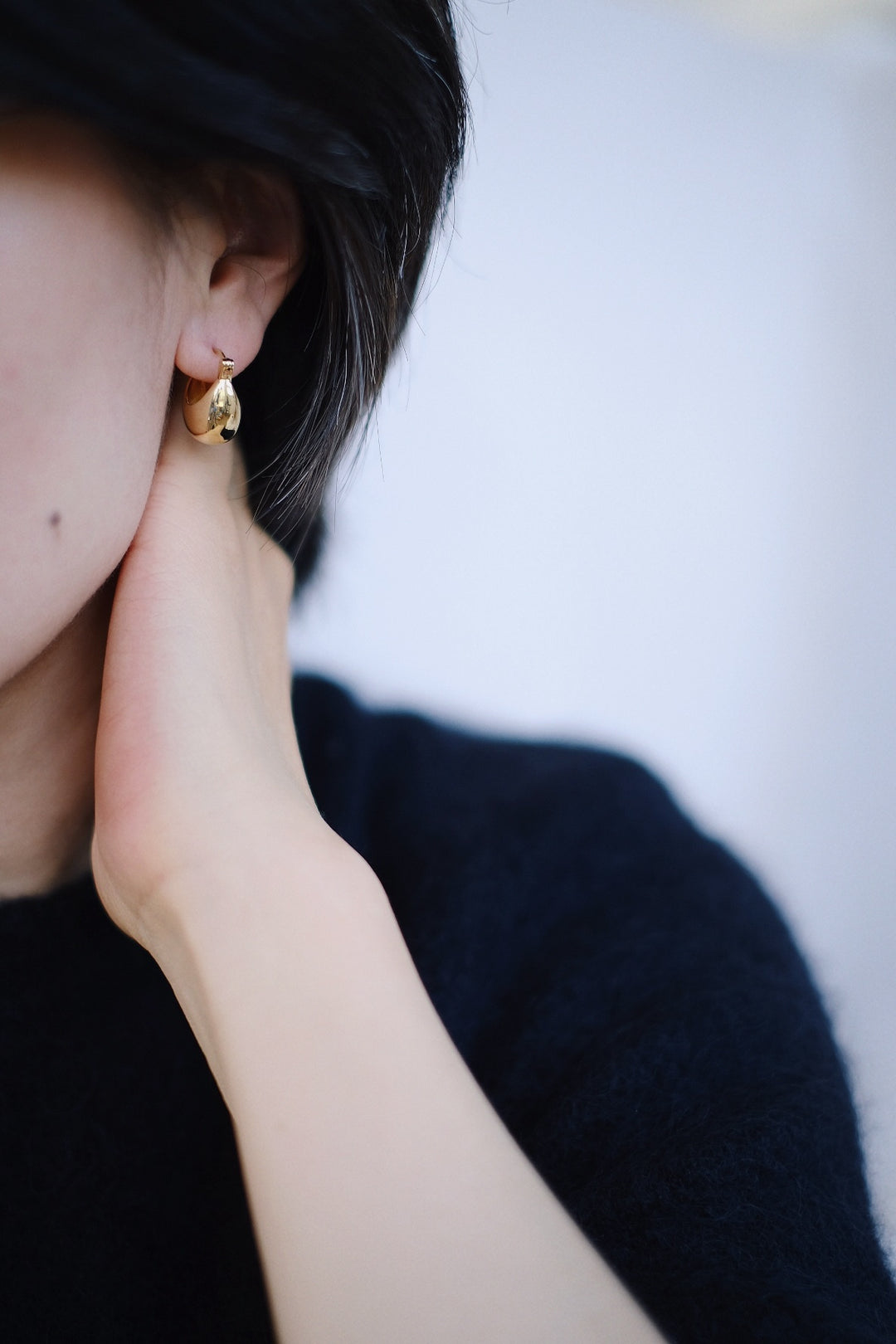 A model wearing the 18k gold-plated Vessel Earrings, showing off their warm, glowing finish and substantial look.