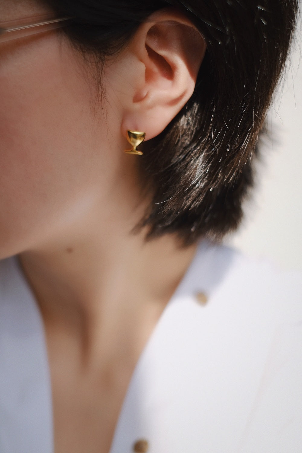 This close-up image focuses on the gold Chic Cheers earrings, emphasizing their luxurious gold-plated finish and the intricate details of the wine glass shape. The studs’ gleaming surface and refined design make them a statement piece for any occasion.