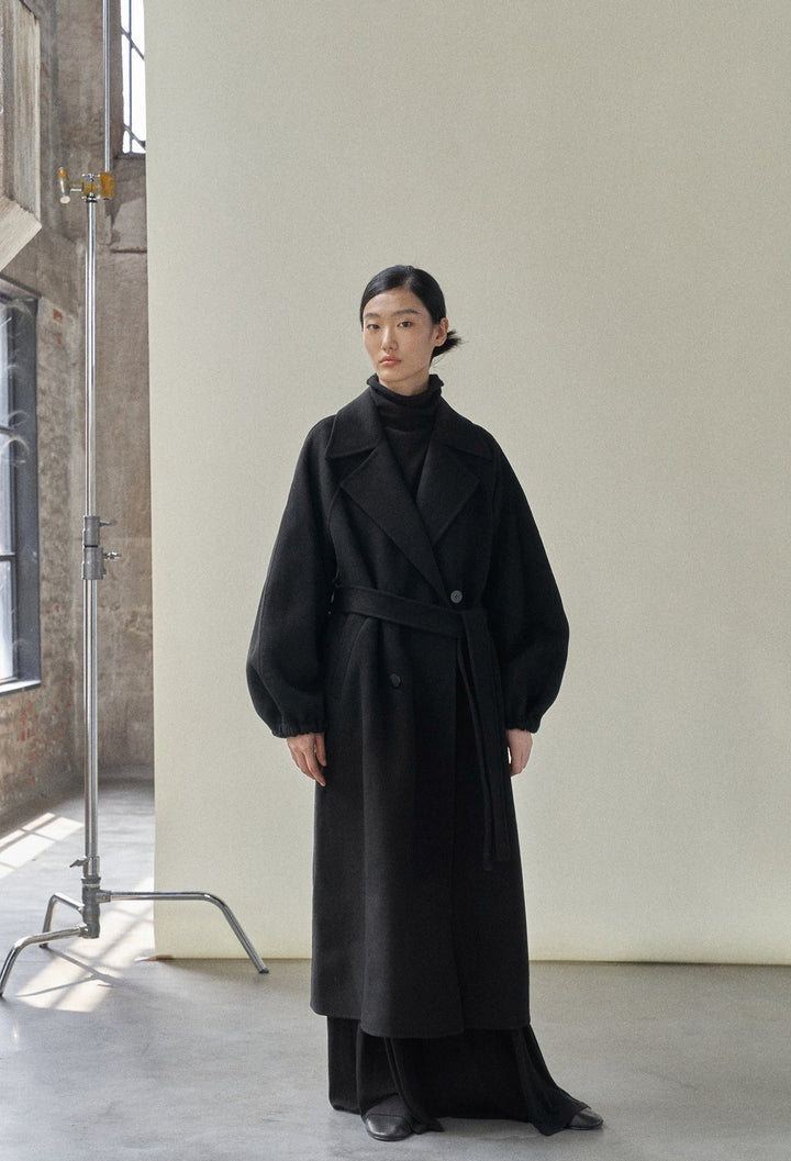 The model in the black coat without the fringe scarf, showcasing a clean and refined look.