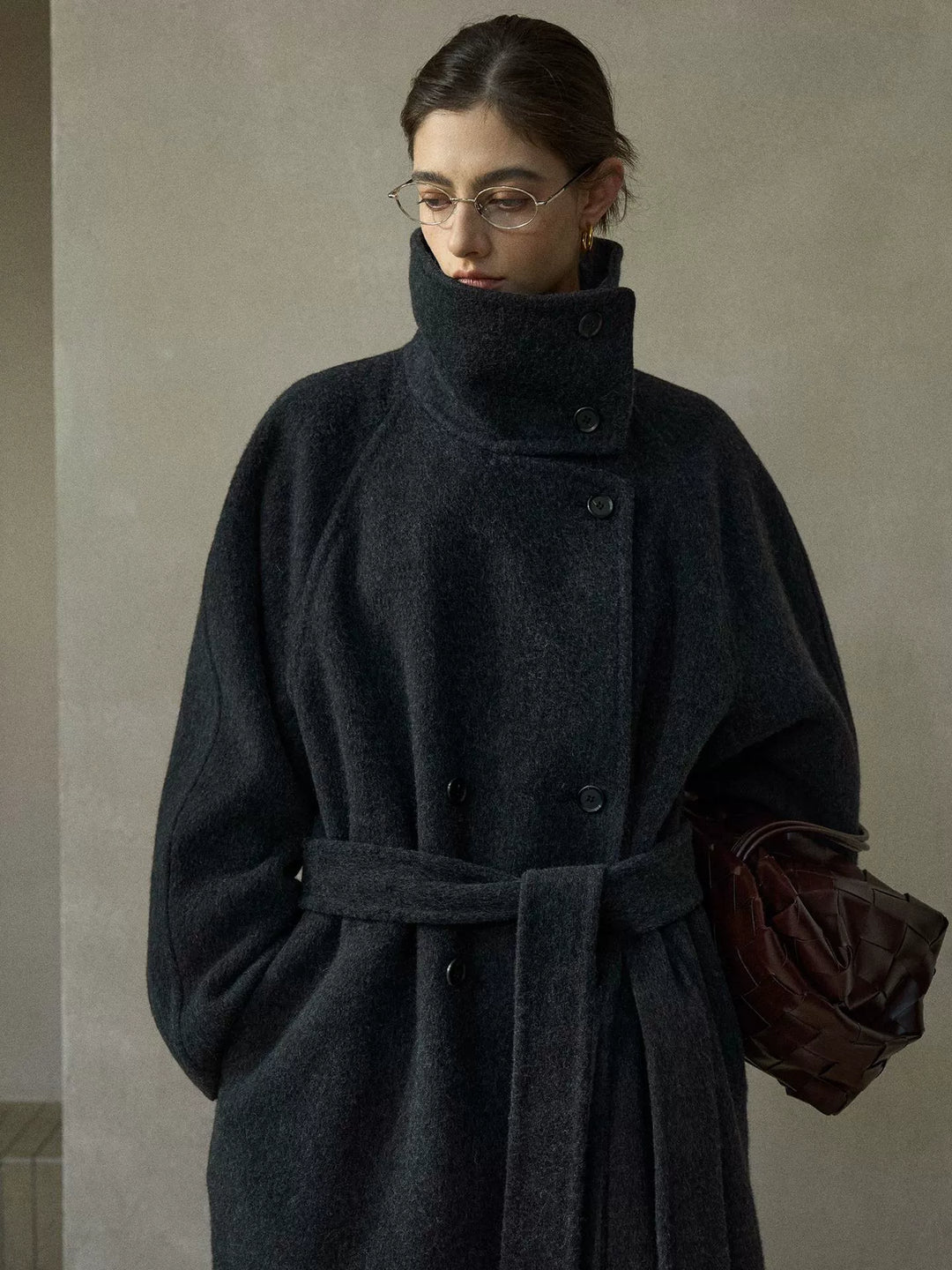 Close-up of charcoal grey coat's collar, button closure, and structured tailoring